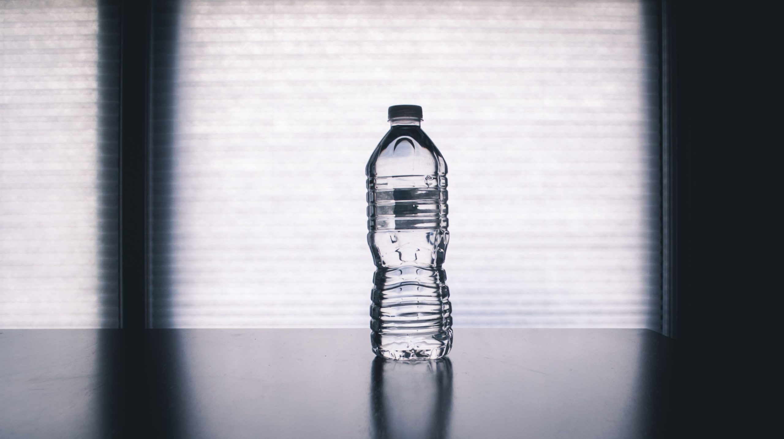 services-01 Stylish photo of a clear plastic water bottle on a reflective surface with a soft shadow.