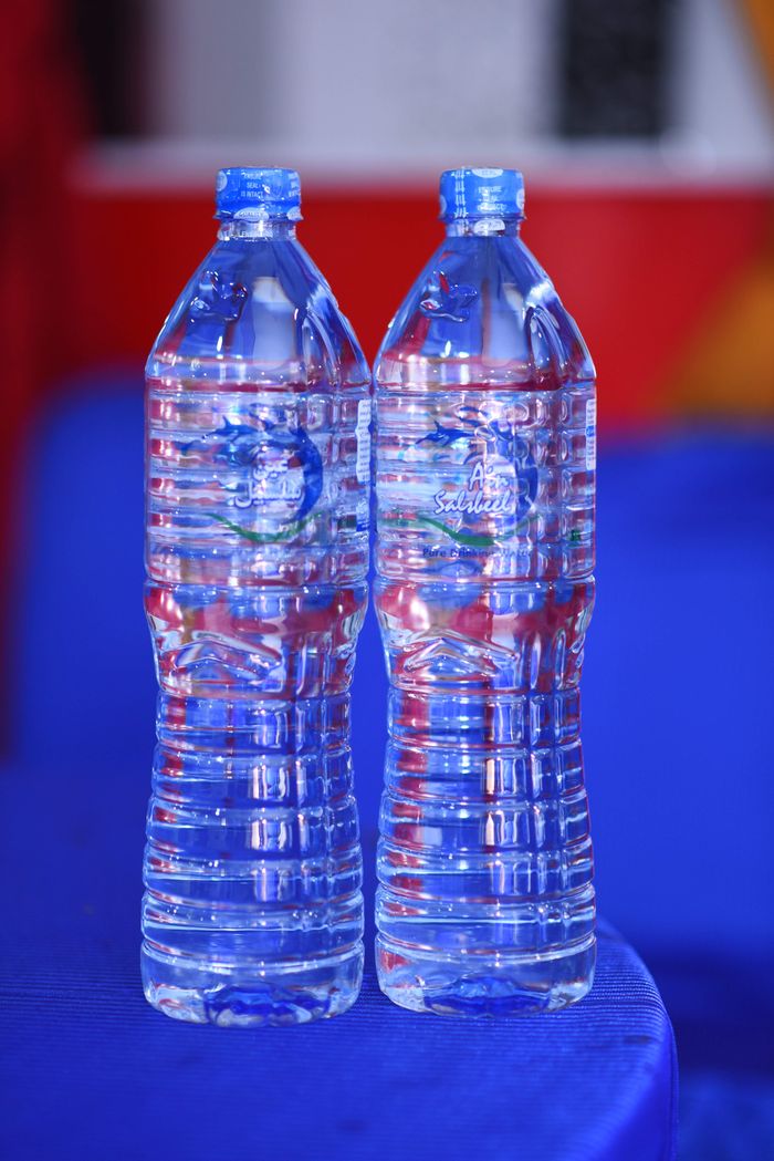 about-02 Two plastic water bottles on a blue table with colorful backdrop.