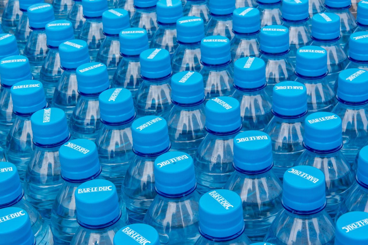 services-03 Close-up of stacked plastic water bottles with blue caps, highlighting recycling and plastic use.