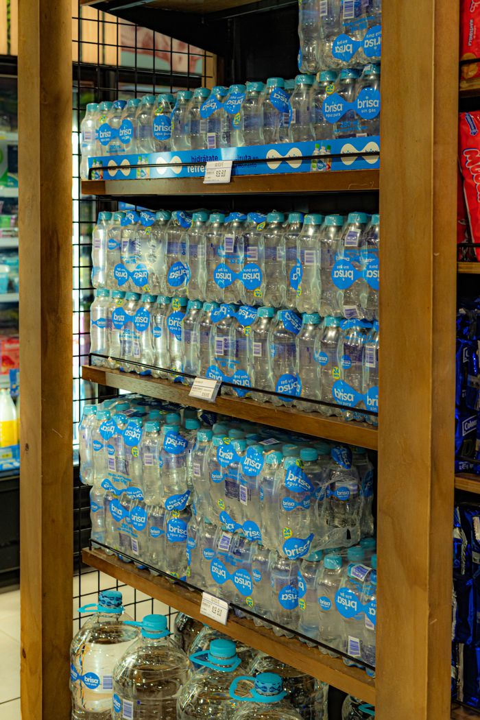 why-choose-us Bottled water neatly arranged on supermarket shelves displaying consumer goods.